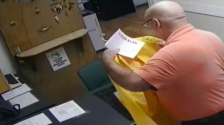 Police chief Anthony Campo seen placing the “Ku Klux Klan” sign on his Black colleague’s yellow raincoat