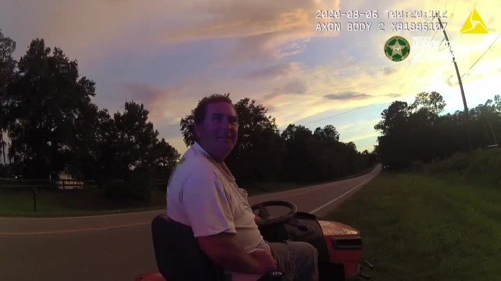 still of deputy's bodycam footage showing Paul Burke sitting on his lawnmower after having been pulled over