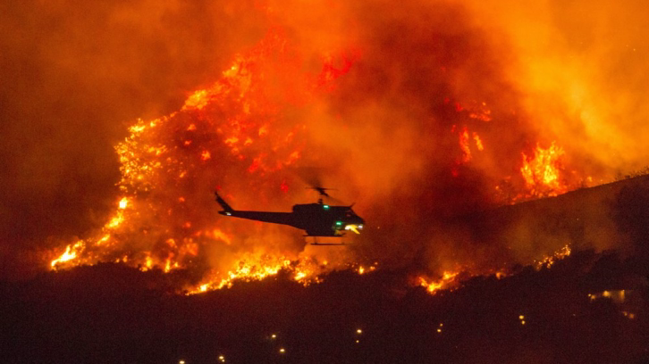 A helicopter prepares to drop water at a wildfire in Yucaipa, CA