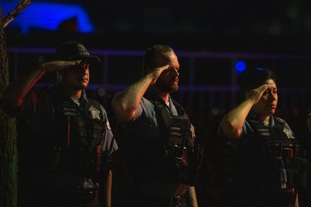 Chicago police officers salute a procession