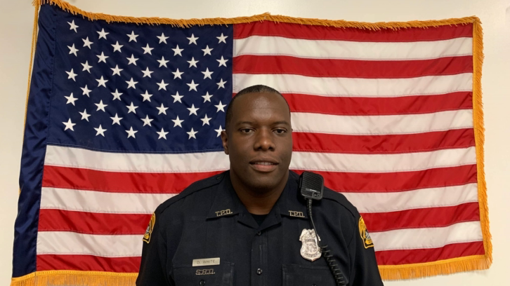 Florida officer Delvin White in his police uniform in front of the American flag