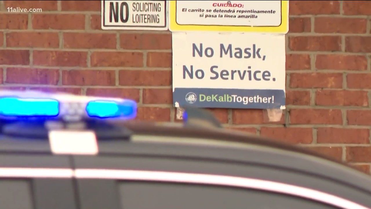 A sign saying 'No Mask, No Service' outside the Big Bear grocery store in DeKalb County above a parked police car