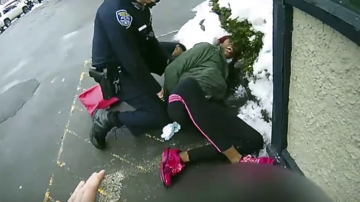 Still of bodycam footage showing an officer struggling to subdue a Black woman suspected of shoplifting