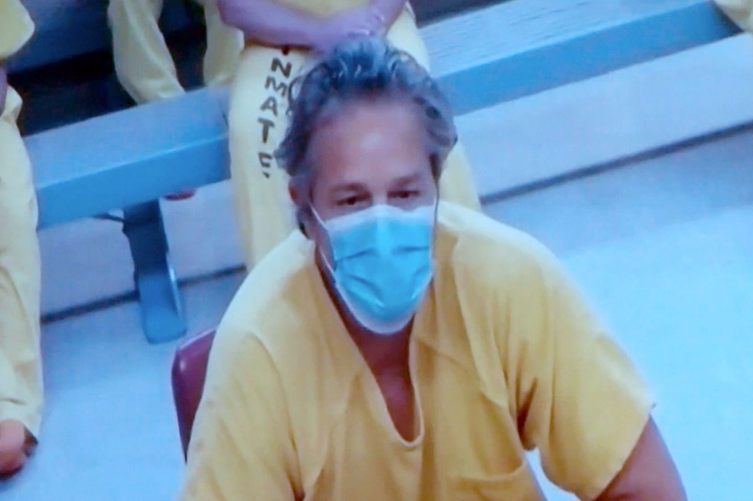 masked defendant in prison jumpsuit