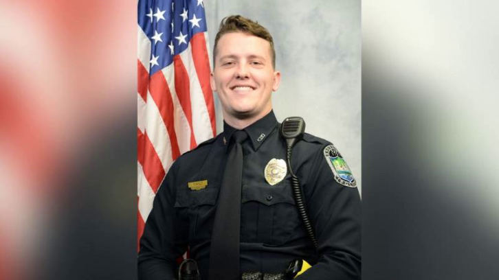 Tanner Holt posing in police uniform with US flag in background