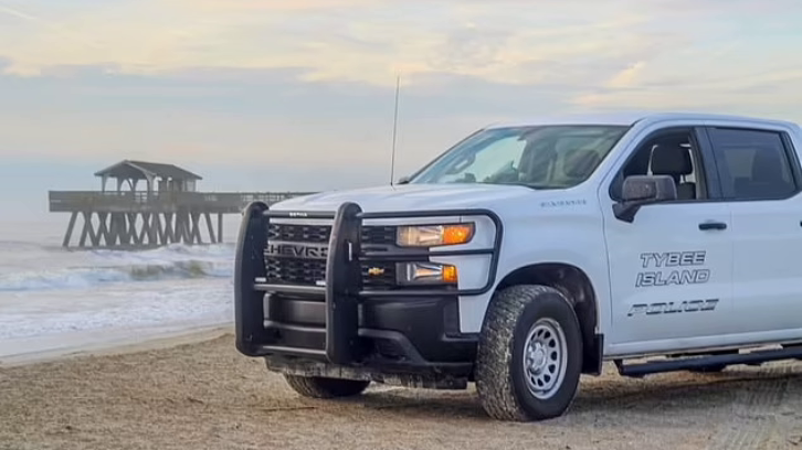 Tybee Island Police vehicle parked on the beach by the water with a pier in the background.