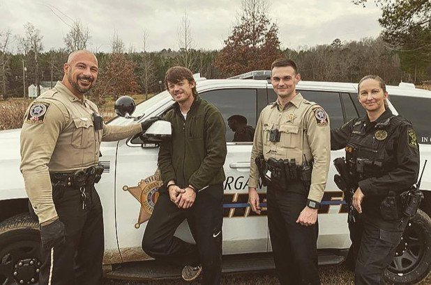 Arrestee Heath Swafford of Lacey's Spring, Alabama, smiles as he poses with arresting officers