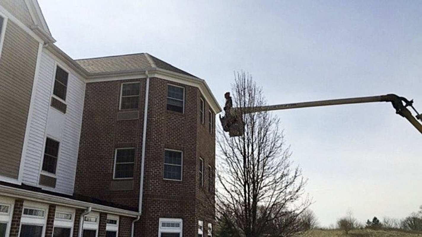 Ohio arborist Charley Adams standing outside his mom's third-story nursing home room in the elevated bucket of his firm's bucket truck