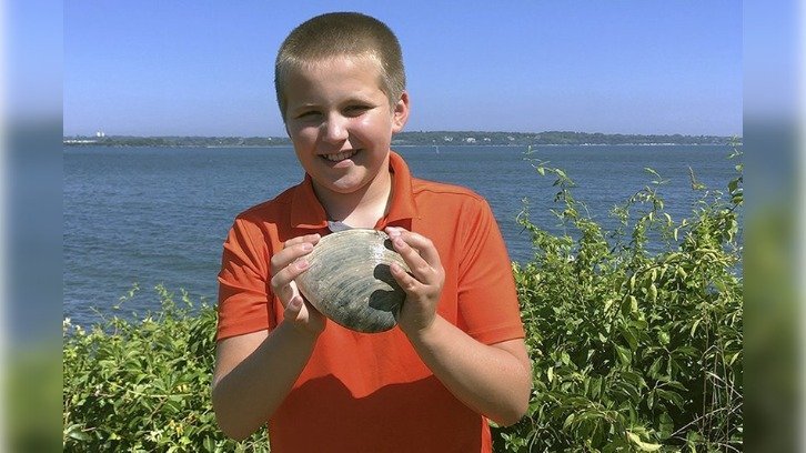 Cooper Monaco holding the large quahog he found Monday while clamming with his grandfather in Westerly, Rhode Island