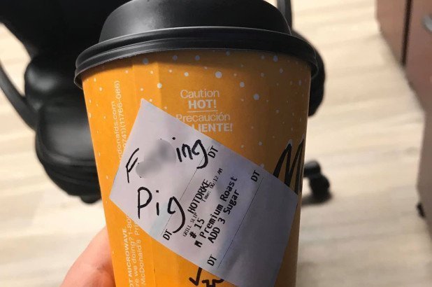 Yellow McDonald's coffee cup with handwritten message "F***ing pig"