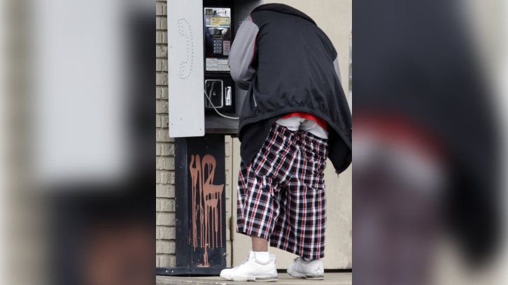 man by phone box wearing saggy pants