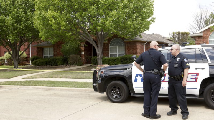 Police officers stand outside a suburban Dallas home, where six people were found fatally shot after two brothers allegedly planned to kill four family members and themselves