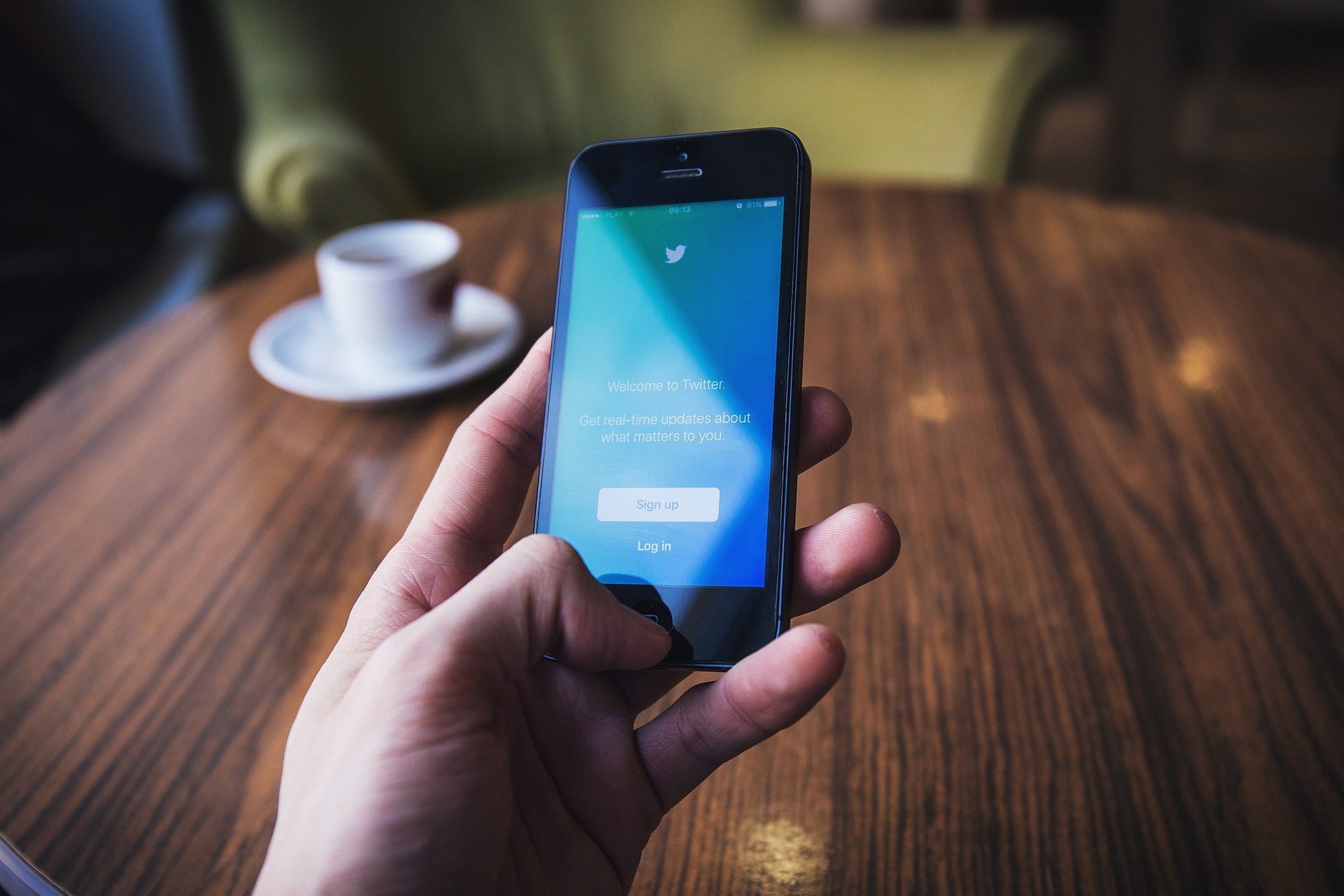 stock photo of hand holding smartphone displaying Twitter